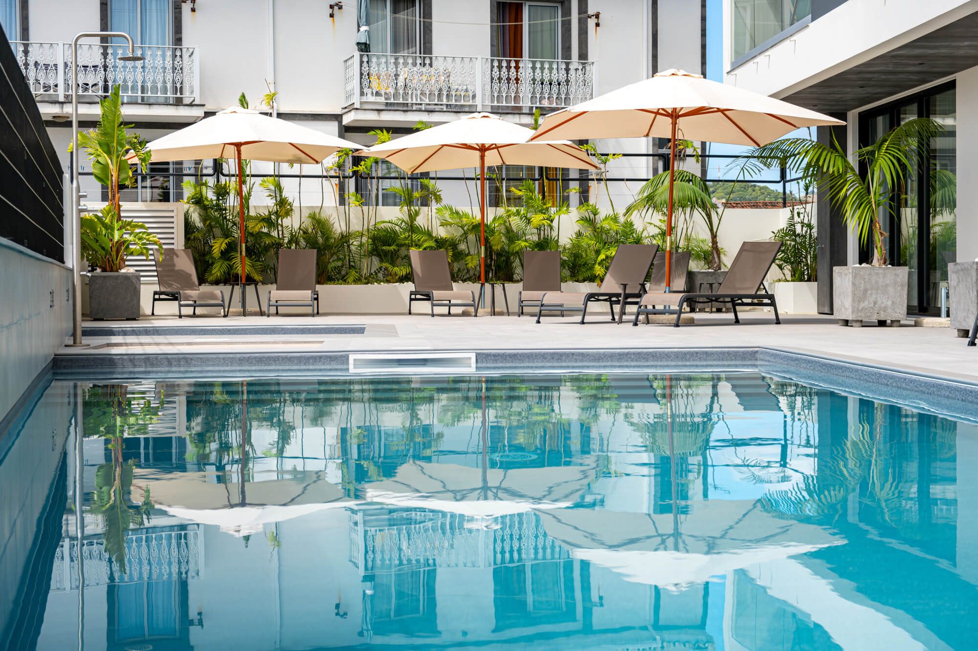 Piscina do Alto do Forte rodeada de plantas tropicais com reflexo na água